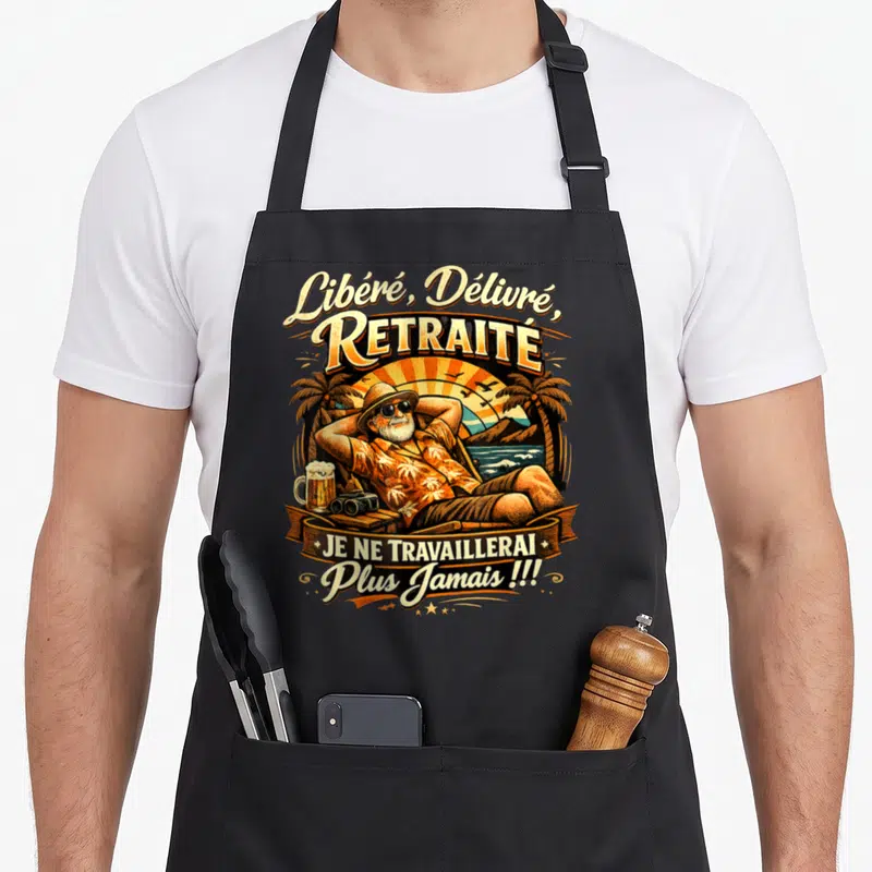 Tablier de cuisine noir avec illustration d'un retraité relaxant sous les palmiers et une bière.
