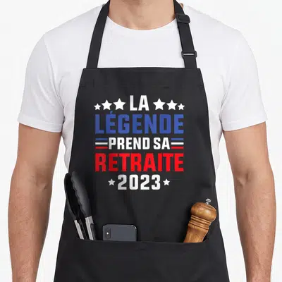 Tablier de cuisine noir avec inscription La Légende Prend Sa Retraite 2023 en bleu blanc rouge et étoiles blanches.