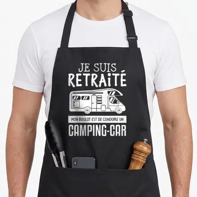 Tablier de cuisine noir avec inscription Je suis retraité et illustration d'un camping-car blanc stylisé.
