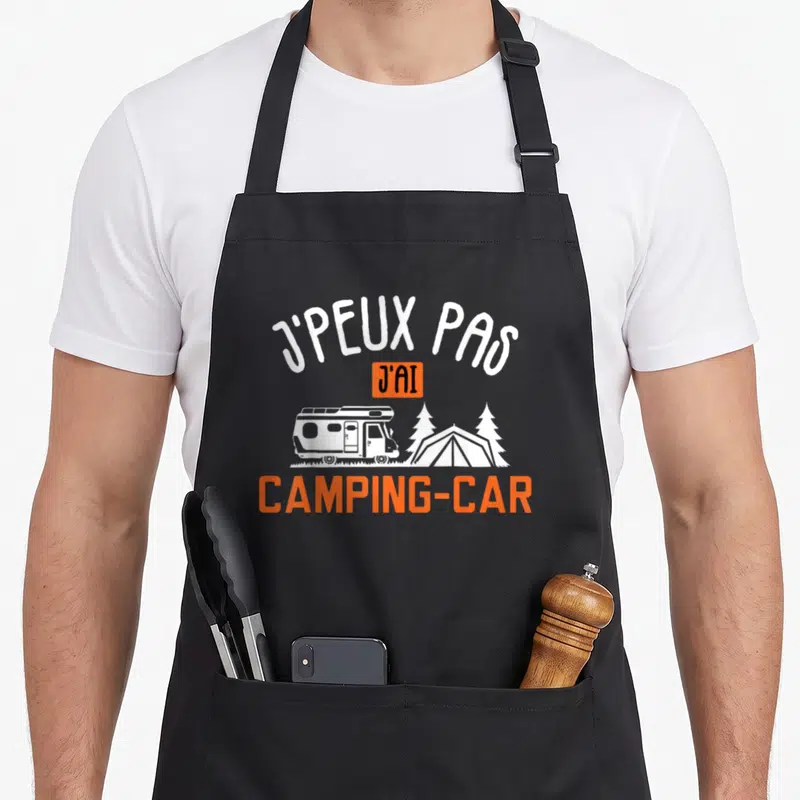 Tablier de cuisine noir avec inscription Je peux pas j'ai camping-car et illustration de camping-car blanc sur fond gris.