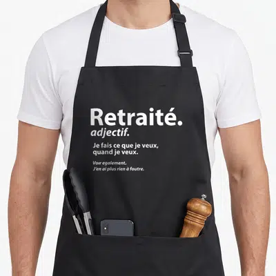 Tablier de cuisine noir avec l'inscription blanche Retraité adjectif et sa définition humoristique sur fond uni.