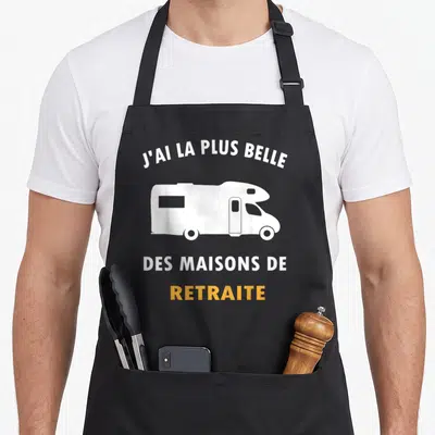 Tablier de cuisine noir avec illustration de camping-car blanc et texte J'ai la plus belle des maisons de retraite en blanc et orange.
