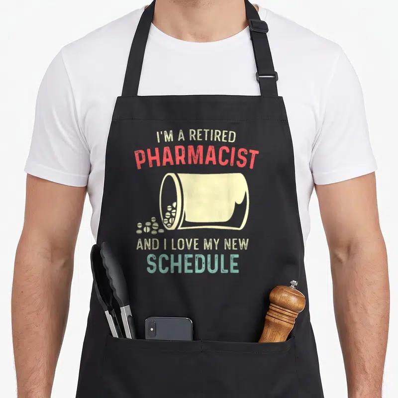 Tablier de cuisine noir avec illustration de flacon de médicaments et texte humoristique sur la retraite professionnelle.