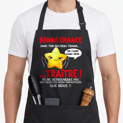 Tablier de cuisine noir orné d'une étoile jaune souriante pointant du doigt avec des textes rouges et blancs humoristiques.