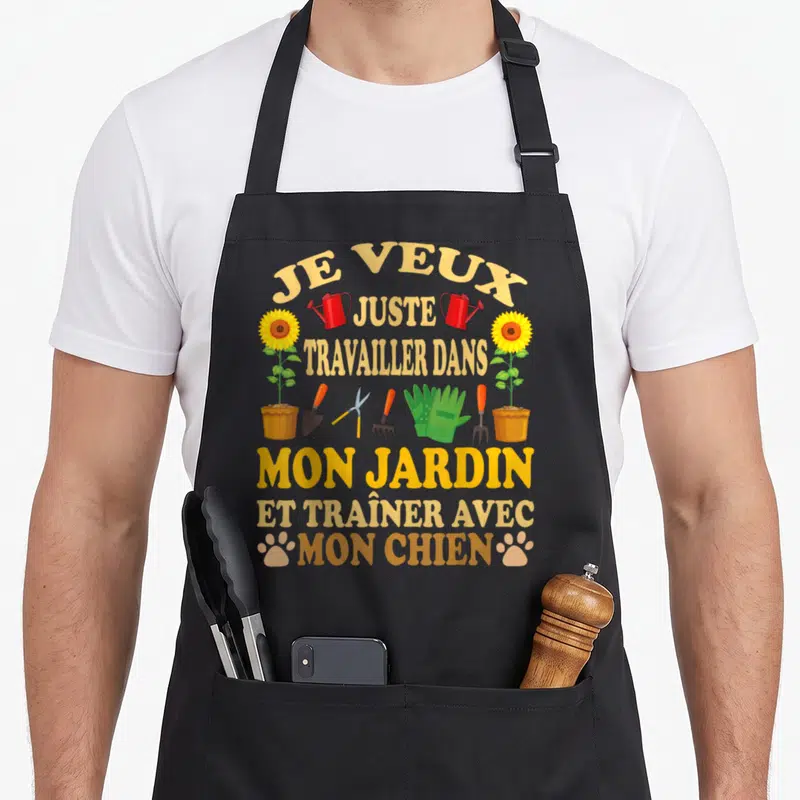 Tablier de cuisine noir avec inscription Je veux juste travailler dans mon jardin et traîner avec mon chien entourée d'outils de jardinage et de fleurs.