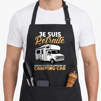 Tablier de cuisine noir avec illustration de camping-car blanc et texte Je suis retraité mon boulot est de conduire un camping-car en orange et blanc.