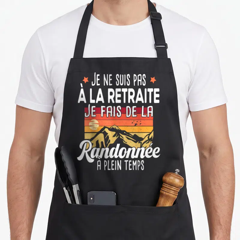 Tablier de cuisine noir avec inscription Je ne suis pas à la retraite randonnée à plein temps et illustration de montagnes orange.