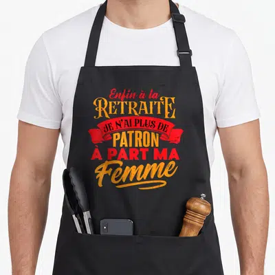 Tablier de cuisine noir avec inscription enfin à la retraite je n'ai plus de patron à part ma femme en orange et rouge.