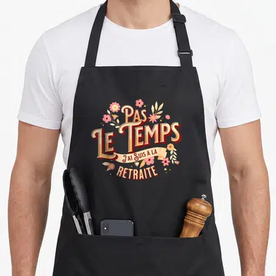 Tablier de cuisine noir avec inscription Pas le temps j'ai suis à la retraite entourée de fleurs roses et jaunes.