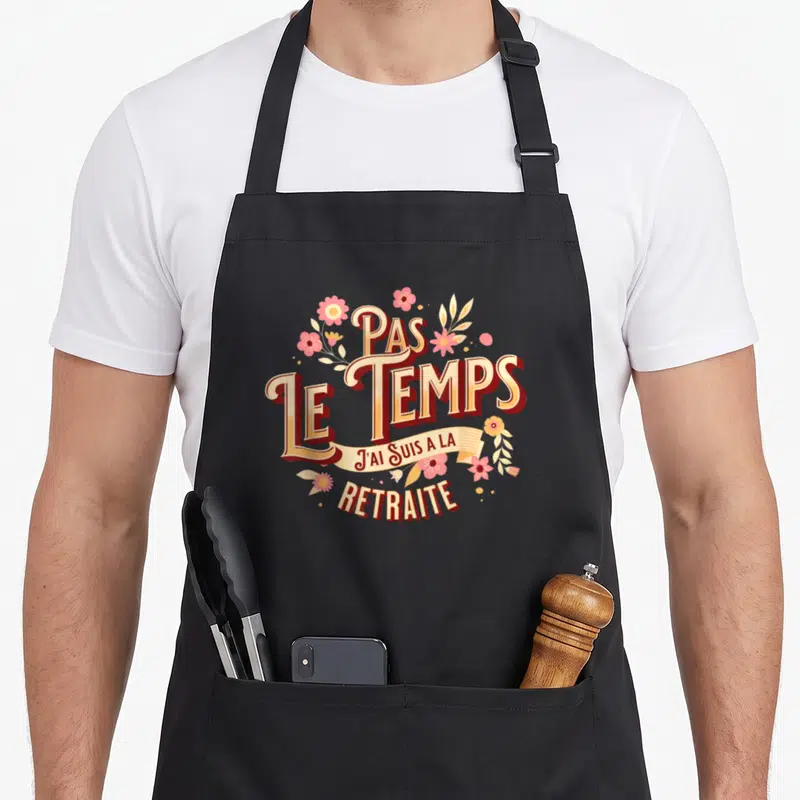Tablier de cuisine noir avec inscription Pas le temps j'ai suis à la retraite entourée de fleurs roses et jaunes.