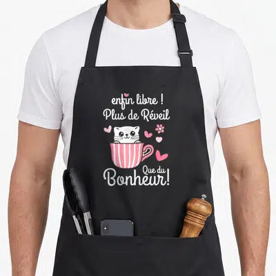 Tablier de cuisine noir avec chat blanc dans une tasse rose et texte enfin libre plus de réveil que du bonheur