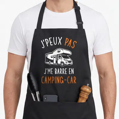 Tablier de cuisine noir avec inscription blanche et orange sur fond gris uni représentant un camping-car stylisé.