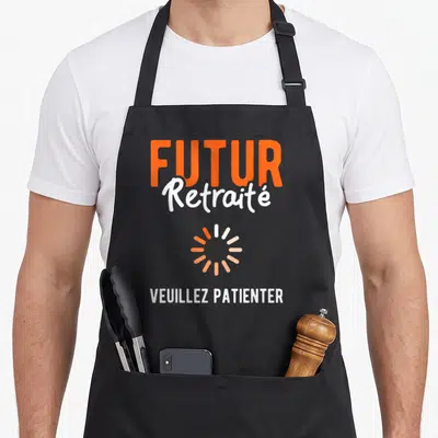 Tablier de cuisine noir avec inscription Futur Retraité et icône de chargement orange.