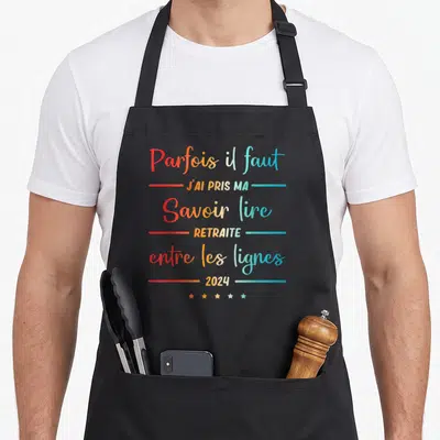 Tablier de cuisine noir avec inscription colorée Parfois il faut savoir lire entre les lignes 2024 et cinq étoiles en bas.
