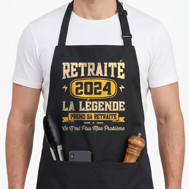 Tablier de cuisine noir avec texte RETRAITÉ 2024 LA LÉGENDE PREND SA RETRAITE en jaune et beige style vintage.
