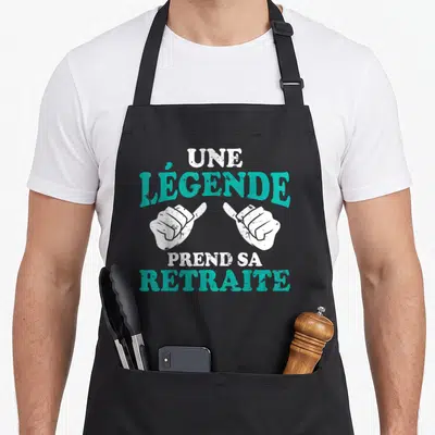 Tablier de cuisine noir avec une légende prend sa retraite et deux mains blanches pointant vers le texte central.