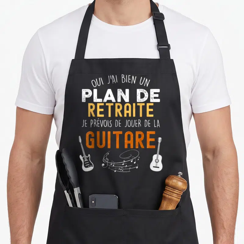 Tablier de cuisine noir avec inscription sur la retraite et illustration de guitares électriques et acoustiques blanches.