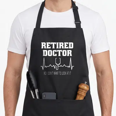 Tablier de cuisine noir avec inscription blanche Retired Doctor et un stéthoscope intégré à une ligne d'électrocardiogramme.