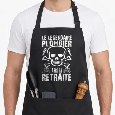 Tablier de cuisine noir avec un crâne blanc entouré de clés à molette et fontaines en style vintage.