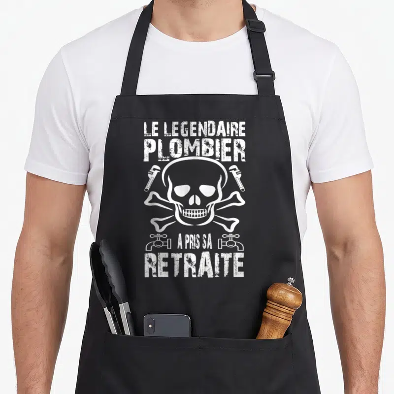 Tablier de cuisine noir avec un crâne blanc entouré de clés à molette et fontaines en style vintage.