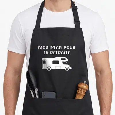 Tablier de cuisine noir avec illustration camping car et texte Mon plan pour la retraite en blanc.