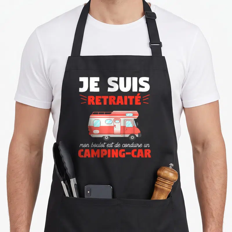 Tablier de cuisine noir avec inscription Je suis retraité et illustration d'un camping-car rouge et blanc stylisé.