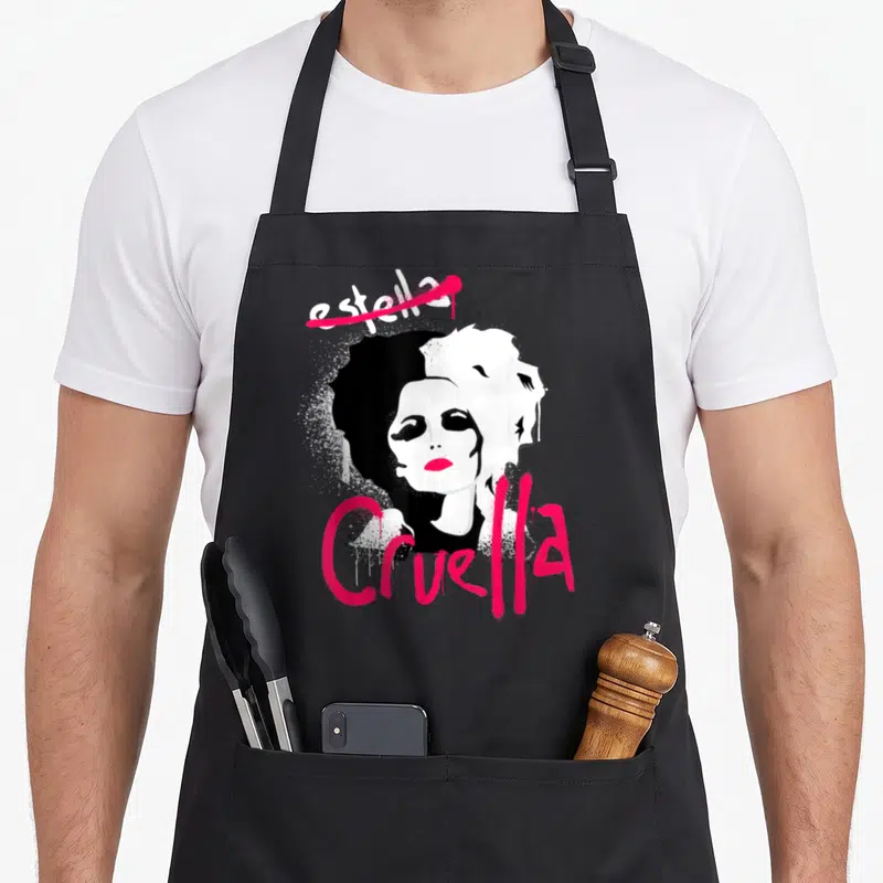 Tablier de cuisine noir avec illustration Cruella Estella au visage bichromique et lettrage spray pink vif.