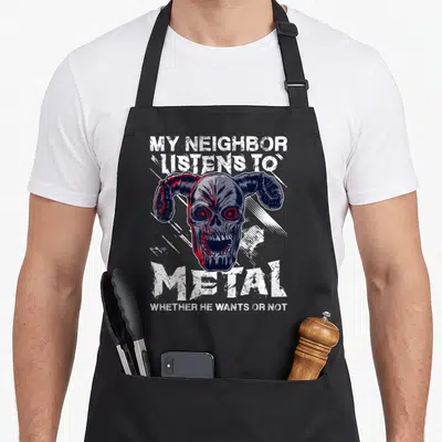 Tablier de cuisine noir avec un crâne cornu aux yeux rouges et du texte blanc stylisé heavy metal.