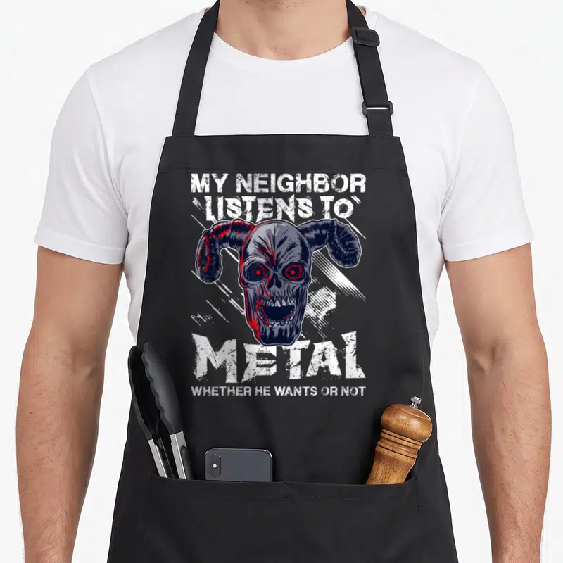Tablier de cuisine noir avec un crâne cornu aux yeux rouges et du texte blanc stylisé heavy metal.