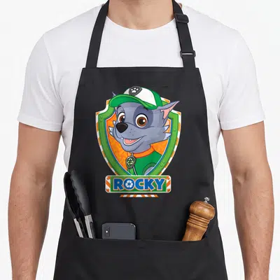 Tablier de cuisine noir avec l'illustration colorée de Rocky le chien recyclage dans un écusson vert et orange.