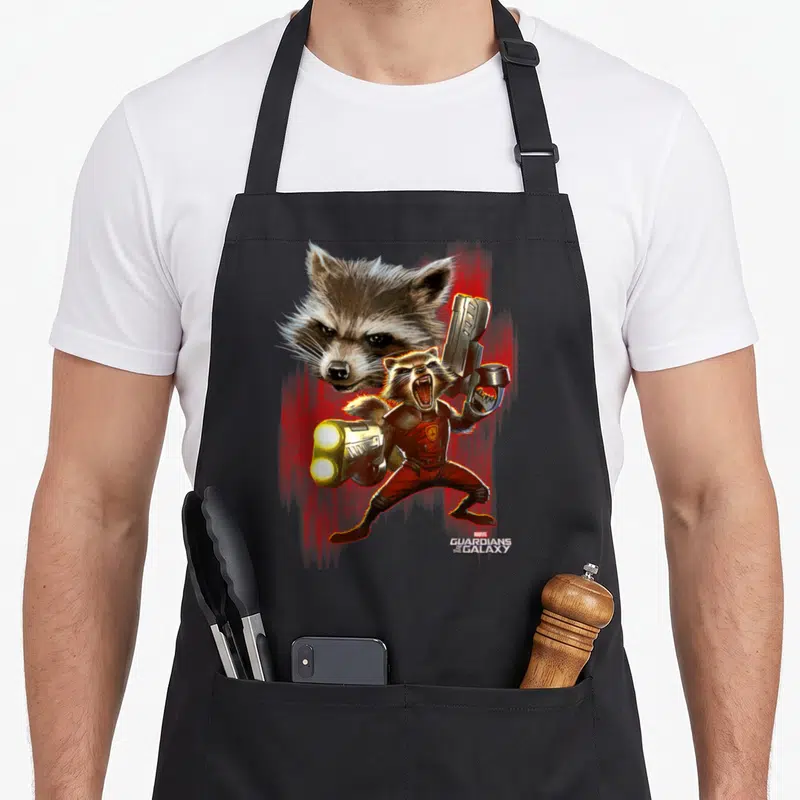 Tablier de cuisine noir avec une illustration colorée de Rocket Raccoon brandissant des armes sur fond rouge vif.