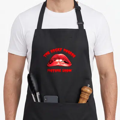 Tablier de cuisine noir avec l'illustration des lèvres rouges et le texte THE ROCKY HORROR PICTURE SHOW en rouge.