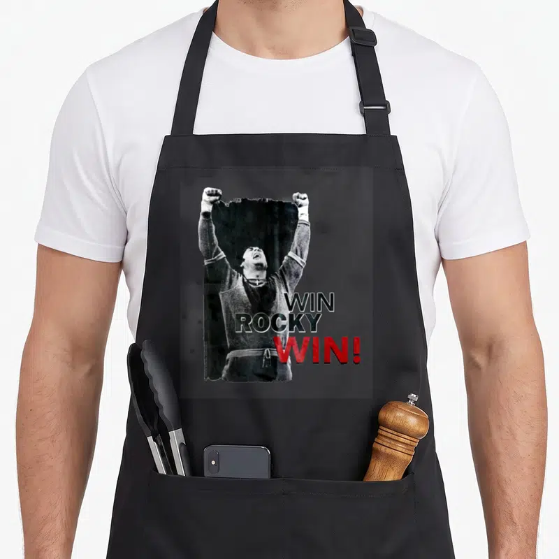 Tablier de cuisine noir avec illustration d'un boxeur levant les bras et le texte Win Rocky Win en noir et rouge.