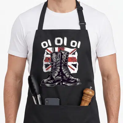 Tablier de cuisine noir illustré par des bottes de combat Oi Oi Punk sur fond de drapeau britannique délavé.