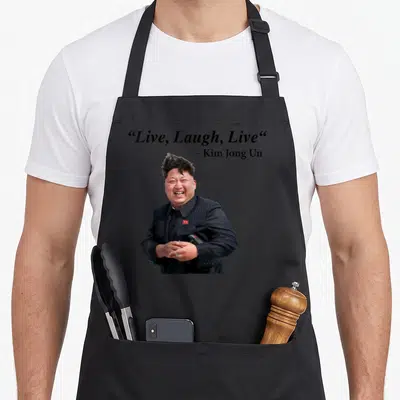 Tablier de cuisine noir avec portrait de Kim Jong Un souriant et texte Live, Laugh, Live au-dessus.