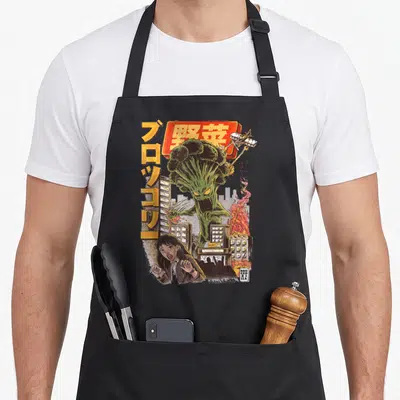 Tablier de cuisine noir avec illustration Broccozilla géant attaquant des bâtiments et une femme effrayée au style manga vintage.