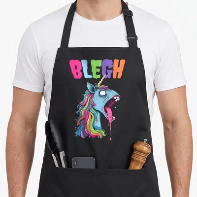 Tablier de cuisine noir avec une licorne bleue aux cheveux arc-en-ciel et la bouche ouverte crachant une substance rose fluide.