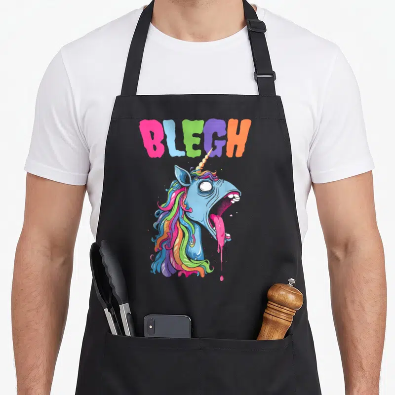 Tablier de cuisine noir avec une licorne bleue aux cheveux arc-en-ciel et la bouche ouverte crachant une substance rose fluide.