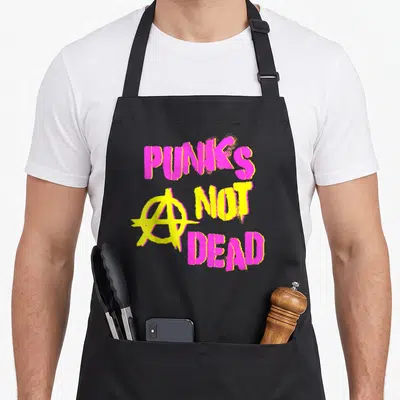 Tablier de cuisine noir avec inscription Punk's Not Dead rose et jaune et symbole anar graffiti.