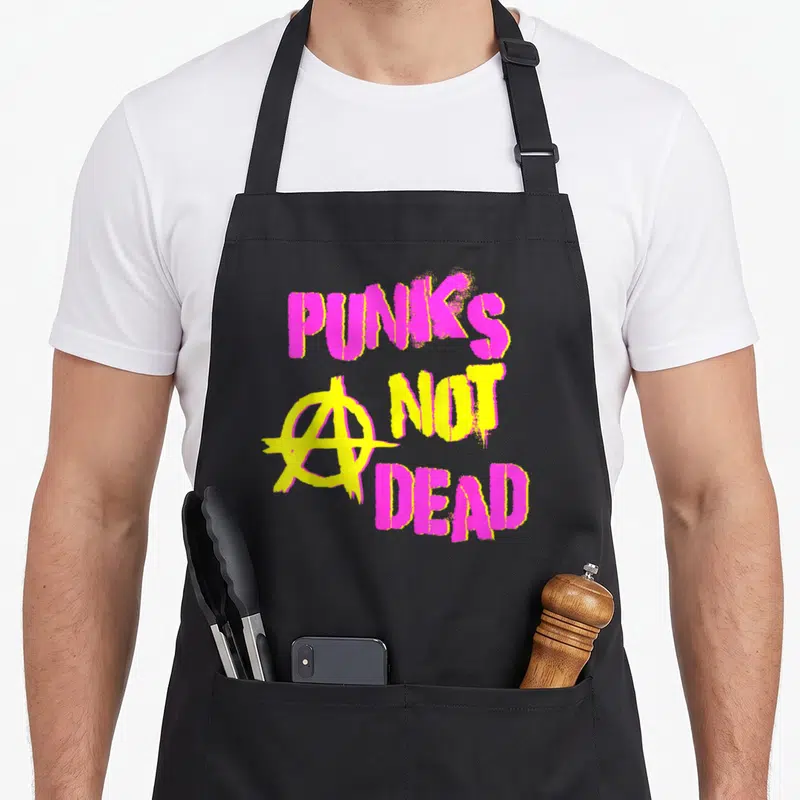 Tablier de cuisine noir avec inscription Punk's Not Dead rose et jaune et symbole anar graffiti.