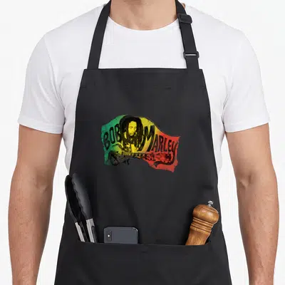Tablier de cuisine noir avec illustration colorée Bob Marley jouant de la guitare sur fond tricolore.