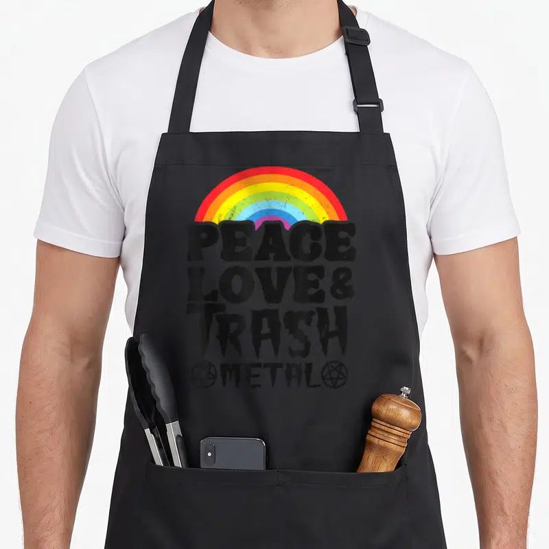 Tablier de cuisine noir avec arc-en-ciel coloré et texte noir Peace Love et Trash Metal en typographie métallique déformée.