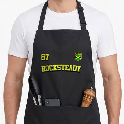 Tablier de cuisine noir avec inscription 67 Rocksteady jaune et écusson drapeau Jamaïque vert noir et jaune.