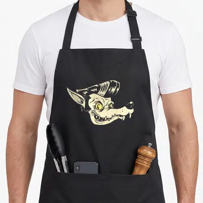 Tablier de cuisine noir avec illustration d'un loup rockabilly aux yeux jaunes et crâne peigné dans un style psychobilly punk art.