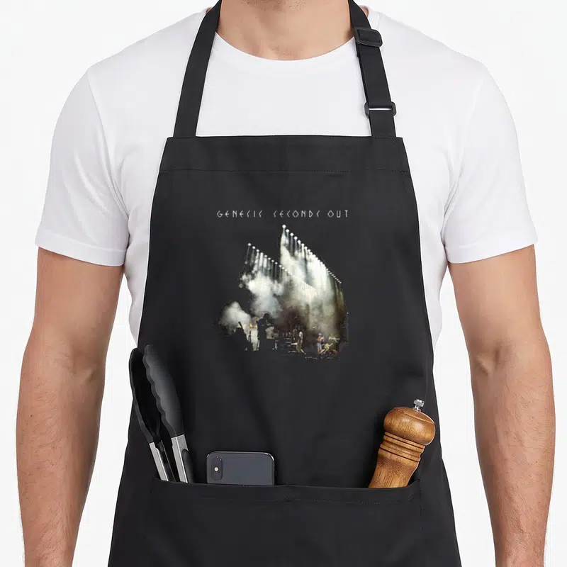 Tablier de cuisine noir avec illustration de scène de concert et texte Genesis Seconds Out en haut.