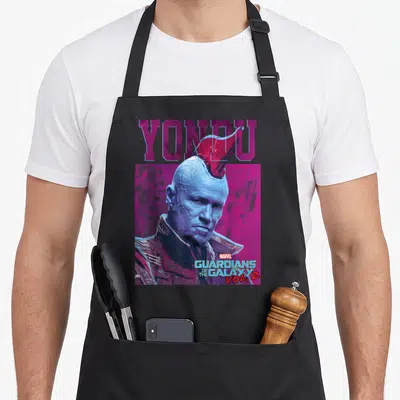Tablier de cuisine noir avec portrait bleu de Yondu, crête rouge et texte Guardians of the Galaxy Vol. 2 sur fond magenta.