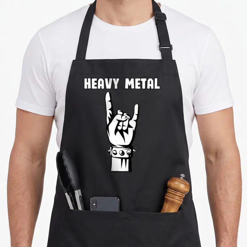 Tablier de cuisine noir avec une illustration blanche représentant une main et l'inscription Heavy Metal au-dessus.