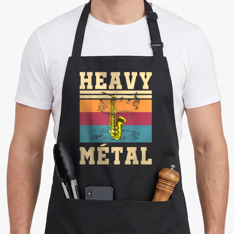 Tablier de cuisine noir avec illustration vintage d'un saxophone doré et le texte Heavy Métal sur fond de bandes colorées.