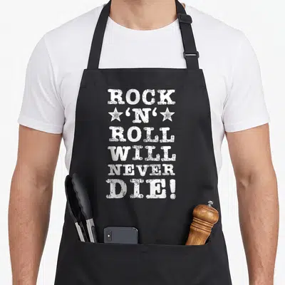 Tablier de cuisine noir avec l'inscription Rock N Roll Will Never Die en lettres blanches usées et deux étoiles.