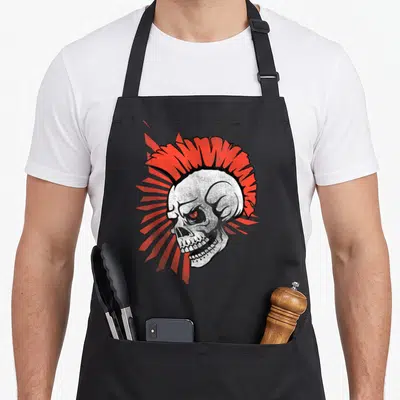Tablier de cuisine noir avec illustration d'un crâne punk à la crête rouge et un œil brillant.